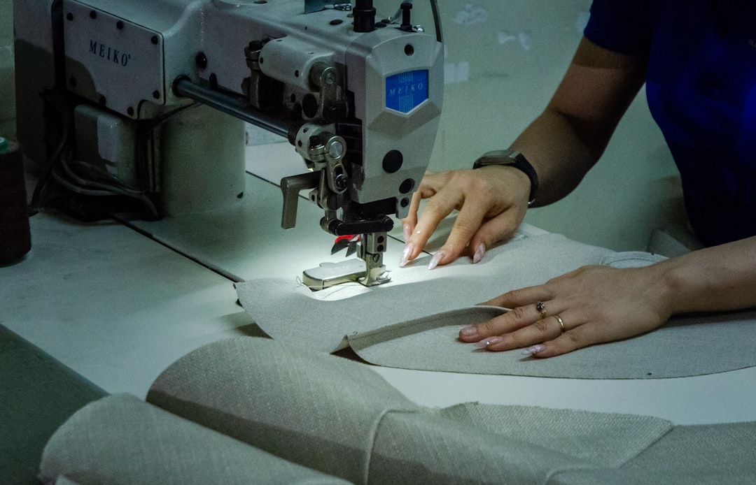 Woman hand sewing fabric — quality craftsmanship detail work in handbag manufacturing